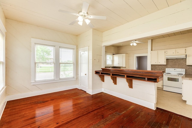 kitchen with under cabinet range hood, white electric range, a ceiling fan, white cabinets, and hardwood / wood-style flooring