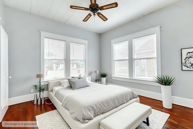 bedroom featuring wood finished floors, baseboards, and multiple windows