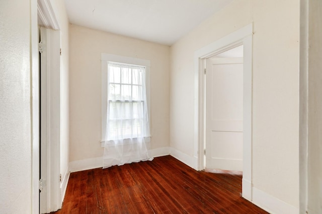 unfurnished room with baseboards and dark wood finished floors