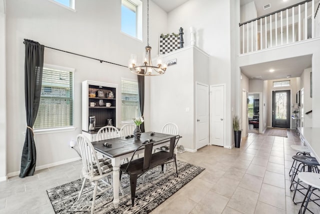 dining space with baseboards, a high ceiling, a wealth of natural light, and a chandelier