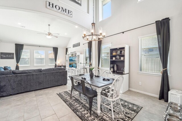 dining area featuring light tile patterned floors, high vaulted ceiling, visible vents, baseboards, and ceiling fan with notable chandelier