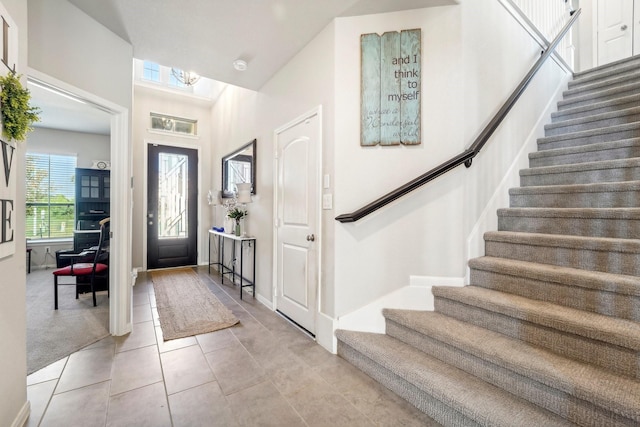 entrance foyer with light tile patterned flooring, baseboards, and stairs