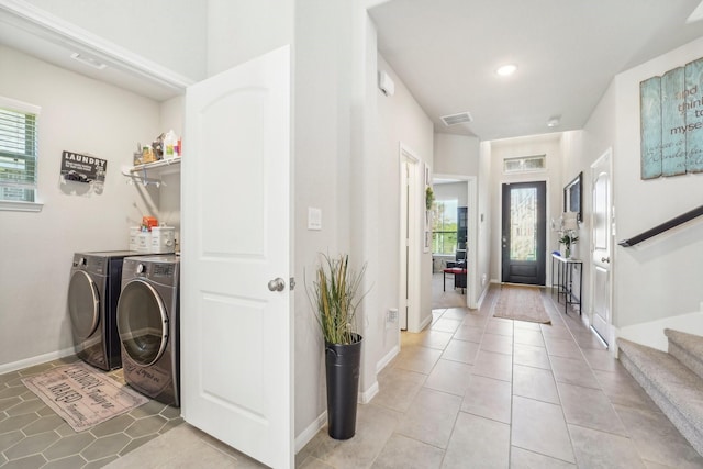 clothes washing area featuring washing machine and dryer, visible vents, light tile patterned floors, and laundry area