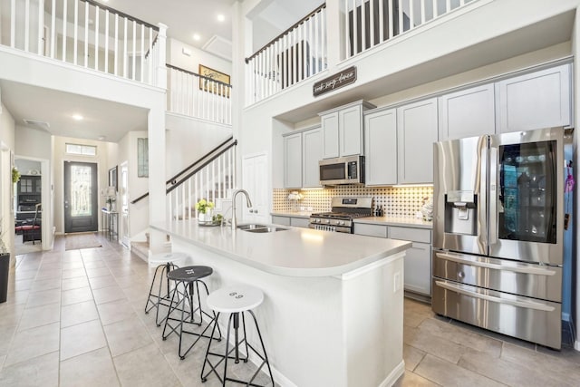 kitchen featuring a sink, a kitchen bar, decorative backsplash, an island with sink, and appliances with stainless steel finishes