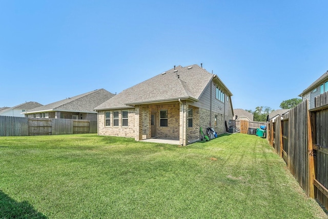back of house featuring a patio, a yard, a fenced backyard, and brick siding