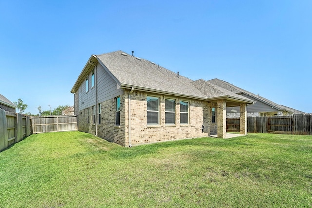 back of property featuring a fenced backyard, brick siding, a shingled roof, and a lawn