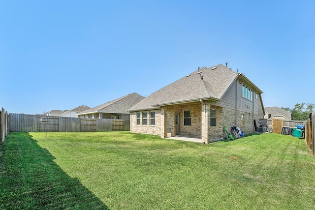 rear view of house with brick siding, a fenced backyard, and a yard