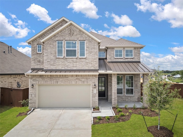 view of front of home featuring a standing seam roof, brick siding, driveway, a front yard, and an attached garage