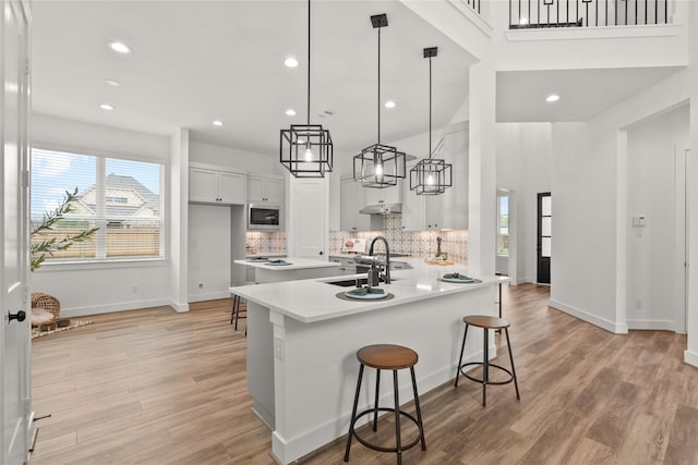 kitchen featuring built in microwave, light countertops, a kitchen bar, light wood-type flooring, and baseboards