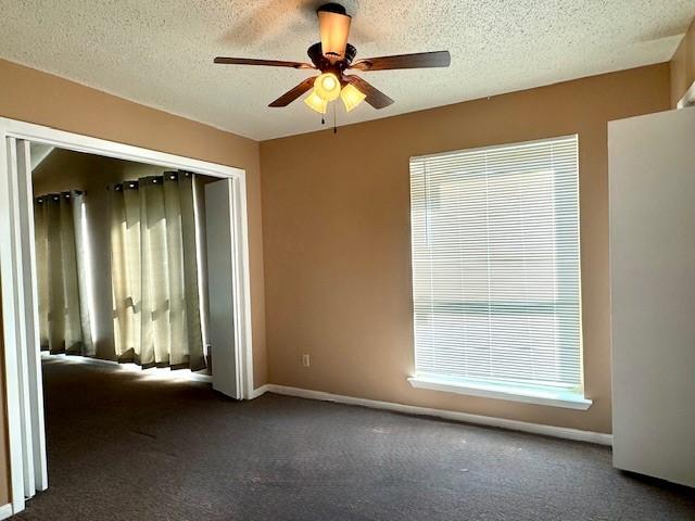 unfurnished room featuring baseboards, ceiling fan, a textured ceiling, and carpet flooring