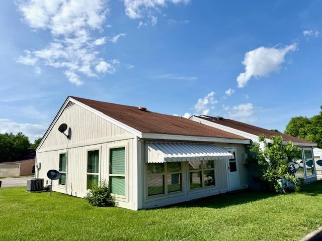rear view of house featuring a lawn and central AC