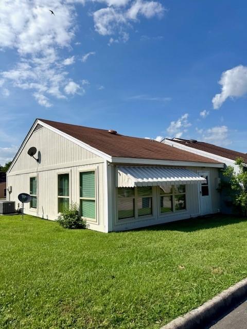 back of property featuring central AC and a yard