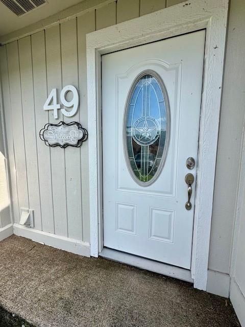 view of exterior entry with visible vents and board and batten siding