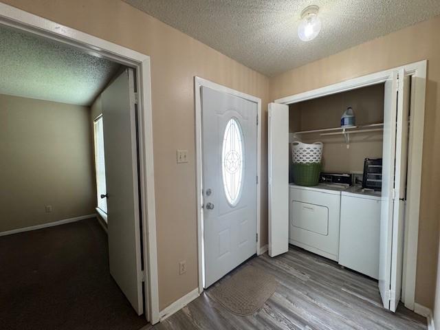 entrance foyer with a textured ceiling, washing machine and clothes dryer, dark wood-type flooring, and baseboards