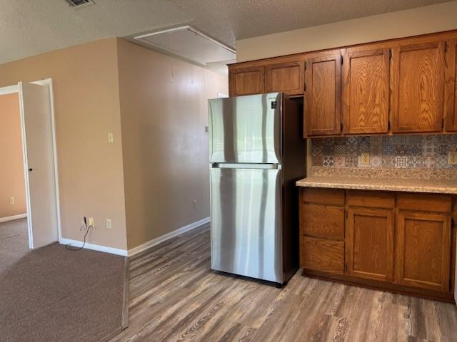 kitchen featuring brown cabinets, light countertops, and freestanding refrigerator