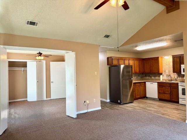 kitchen with visible vents, white appliances, brown cabinetry, and ceiling fan