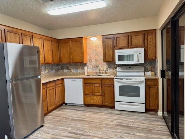 kitchen with light wood-type flooring, brown cabinets, and white appliances