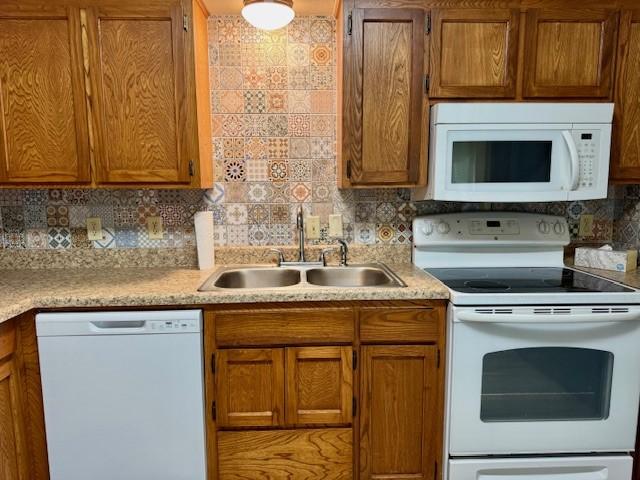 kitchen featuring brown cabinets, decorative backsplash, a sink, light countertops, and white appliances