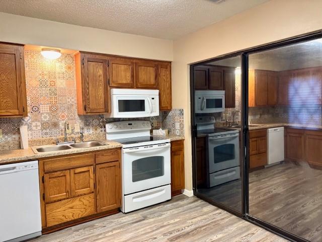 kitchen featuring brown cabinetry, a sink, stainless steel appliances, and light wood-style floors