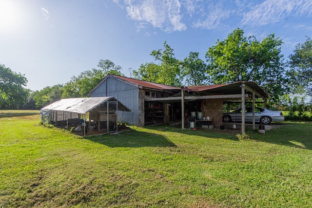 rear view of property featuring a detached carport, exterior structure, an outbuilding, and a lawn