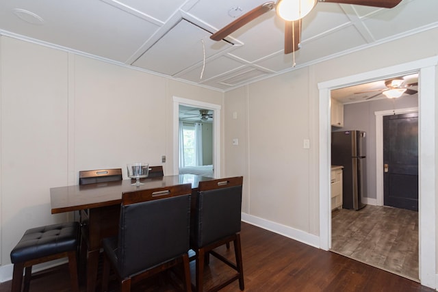dining room featuring baseboards, attic access, ornamental molding, dark wood-type flooring, and a ceiling fan