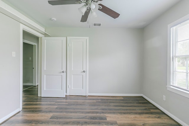 unfurnished bedroom featuring baseboards, visible vents, wood finished floors, and multiple windows