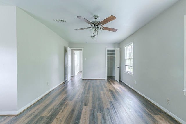 spare room with dark wood-style floors, visible vents, and baseboards