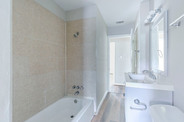 full bath with visible vents, wood finished floors, shower / bathtub combination, and vanity