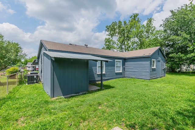 back of property featuring an outdoor structure, a lawn, and fence