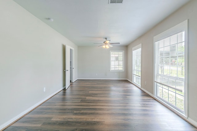 spare room featuring dark wood-style flooring, visible vents, a ceiling fan, and baseboards