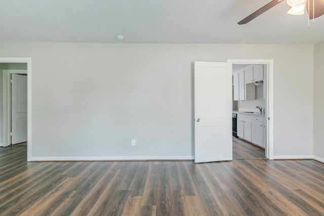 unfurnished room featuring a ceiling fan, a sink, dark wood-style flooring, and baseboards