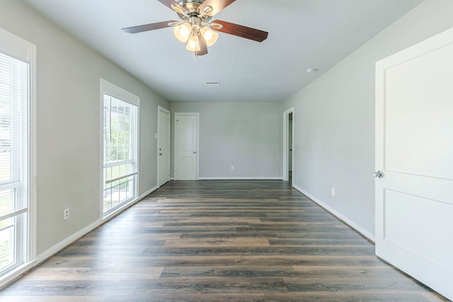 empty room featuring a ceiling fan, visible vents, wood finished floors, and baseboards