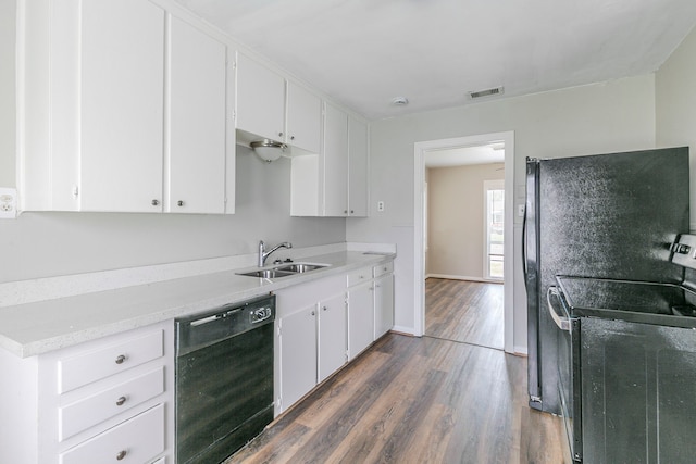 kitchen featuring dark wood-style floors, a sink, black dishwasher, visible vents, and range with electric stovetop