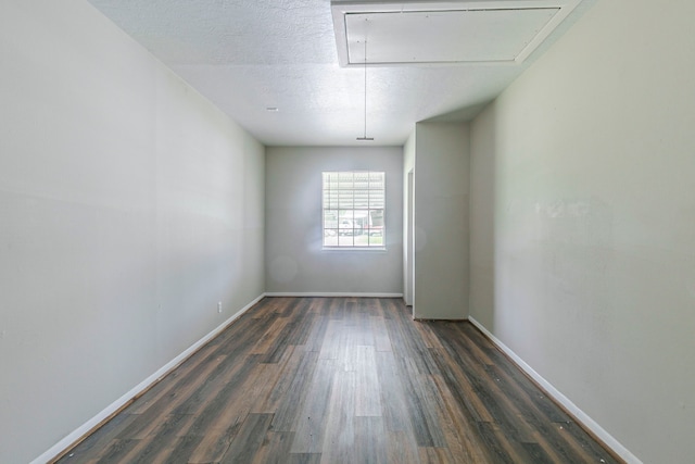 spare room featuring attic access, wood finished floors, and baseboards