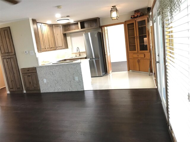 104 Bayside St, Livingston, TX 77351 - kitchen with wood finished floors, freestanding refrigerator, open shelves, light countertops, and a peninsula