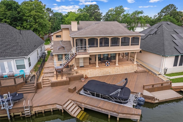 back of house with roof with shingles, boat lift, stucco siding, a sunroom, and stairway