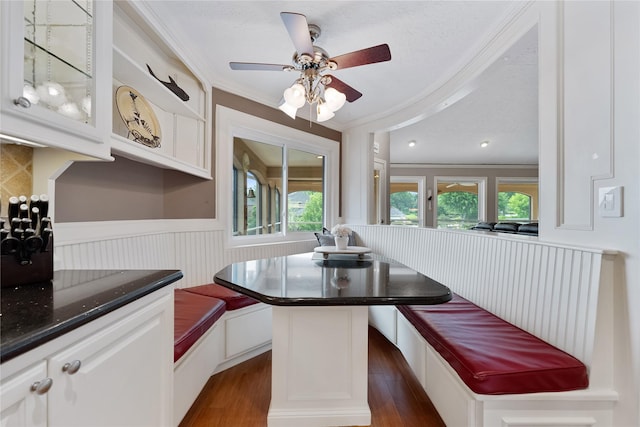 dining space featuring crown molding, dark wood-style flooring, and breakfast area