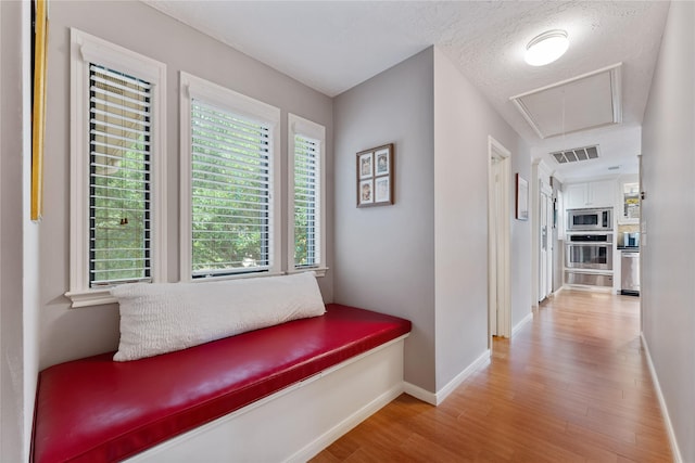 corridor featuring baseboards, attic access, wood finished floors, and visible vents