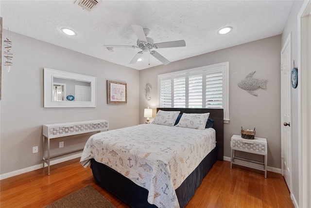 bedroom with baseboards, visible vents, and wood finished floors
