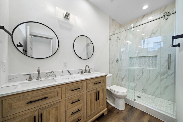 full bath with a marble finish shower, toilet, double vanity, and a sink