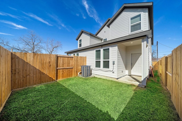 rear view of property featuring a lawn, central AC, and a fenced backyard