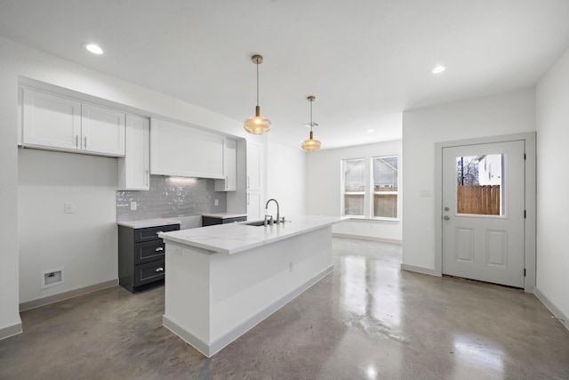 kitchen featuring a sink, concrete flooring, tasteful backsplash, white cabinetry, and baseboards