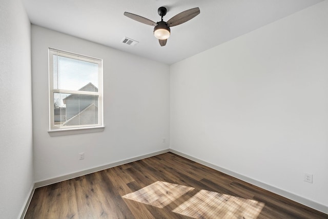 spare room featuring a ceiling fan, visible vents, baseboards, and dark wood-type flooring