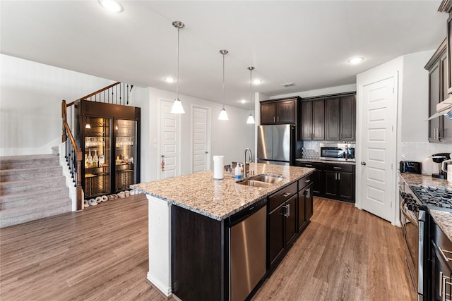 kitchen with light wood-type flooring, appliances with stainless steel finishes, decorative backsplash, and a sink