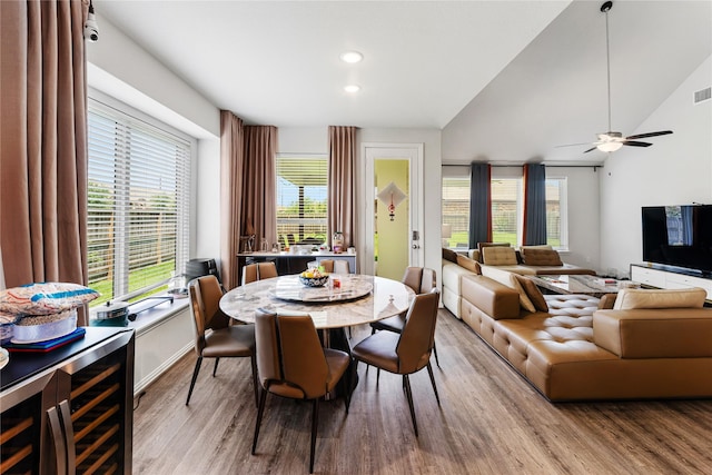 dining space with beverage cooler, light wood-type flooring, visible vents, a ceiling fan, and lofted ceiling