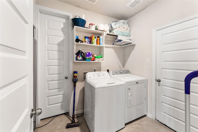 clothes washing area featuring light tile patterned flooring, visible vents, washing machine and clothes dryer, and laundry area