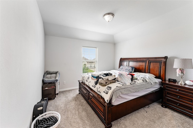 bedroom with lofted ceiling, light colored carpet, and baseboards