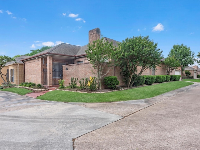 view of front of property featuring brick siding, a chimney, a front yard, and a garage