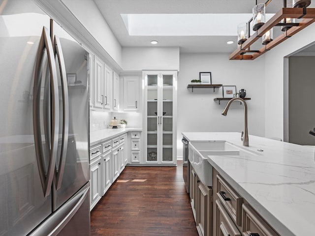 kitchen featuring decorative backsplash, dark wood finished floors, a sink, stainless steel appliances, and white cabinetry