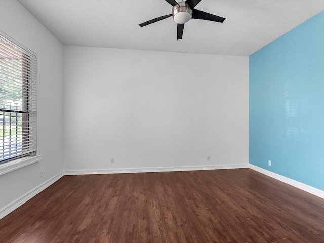 empty room with baseboards, a ceiling fan, and dark wood-style flooring